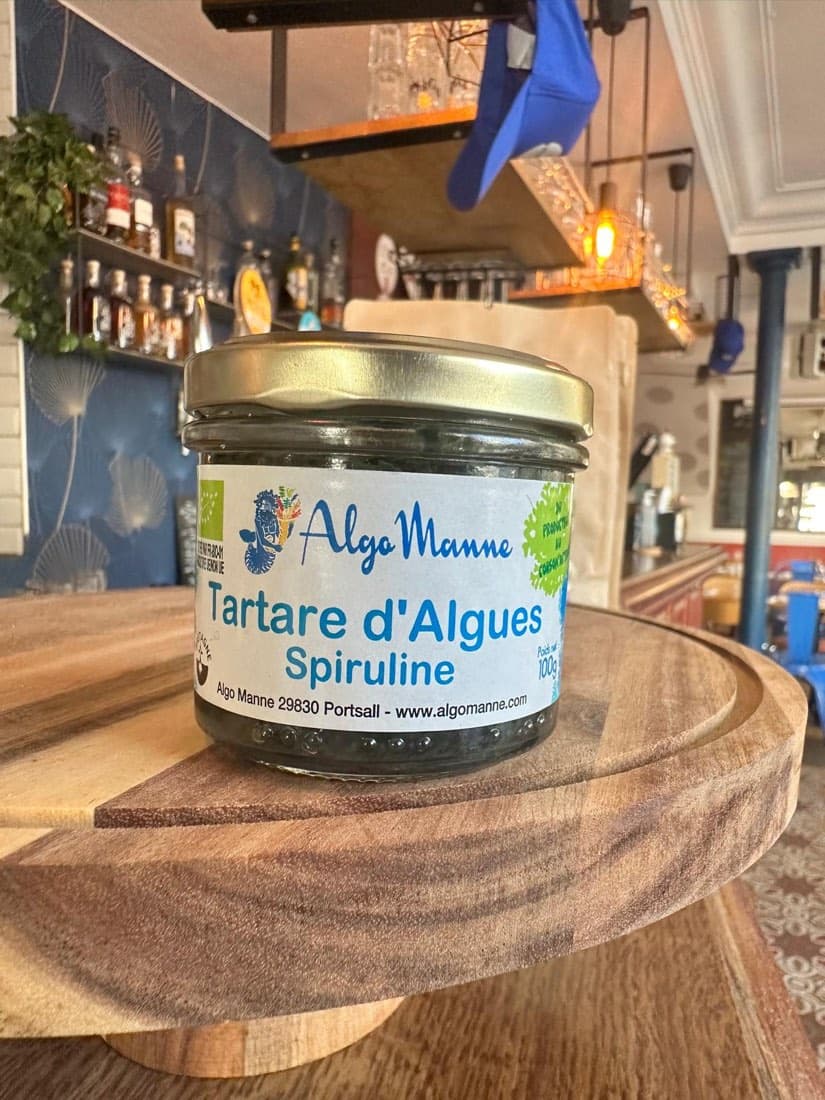 Un pot de tartare d’algues à la spiruline AlgoManne sur une planche en bois à l’épicerie de Ty Louis
